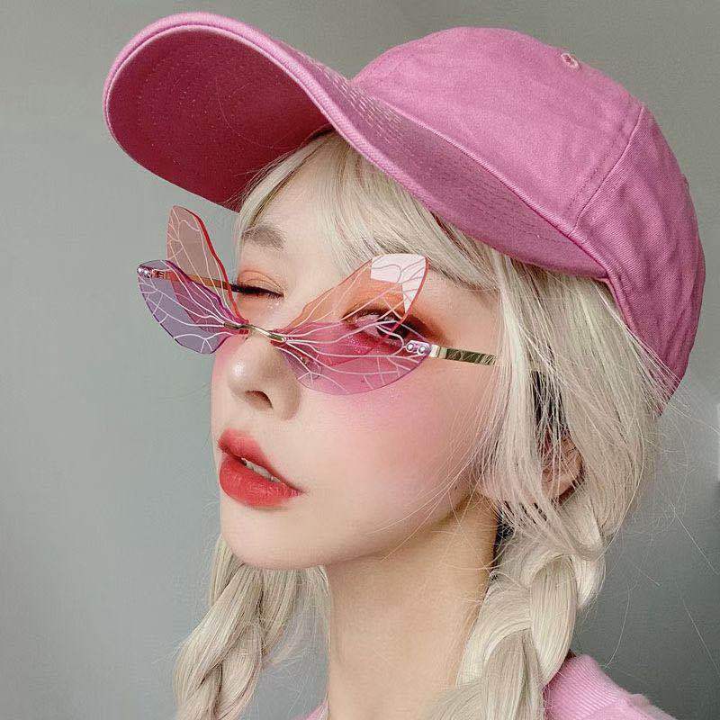Person wearing a pink cap and butterfly sunglasses against a gray background